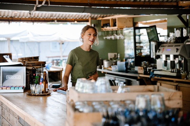 Lachende medewerker aan het werk in de buitenbar van Terraseiland Fort aan de Klop.